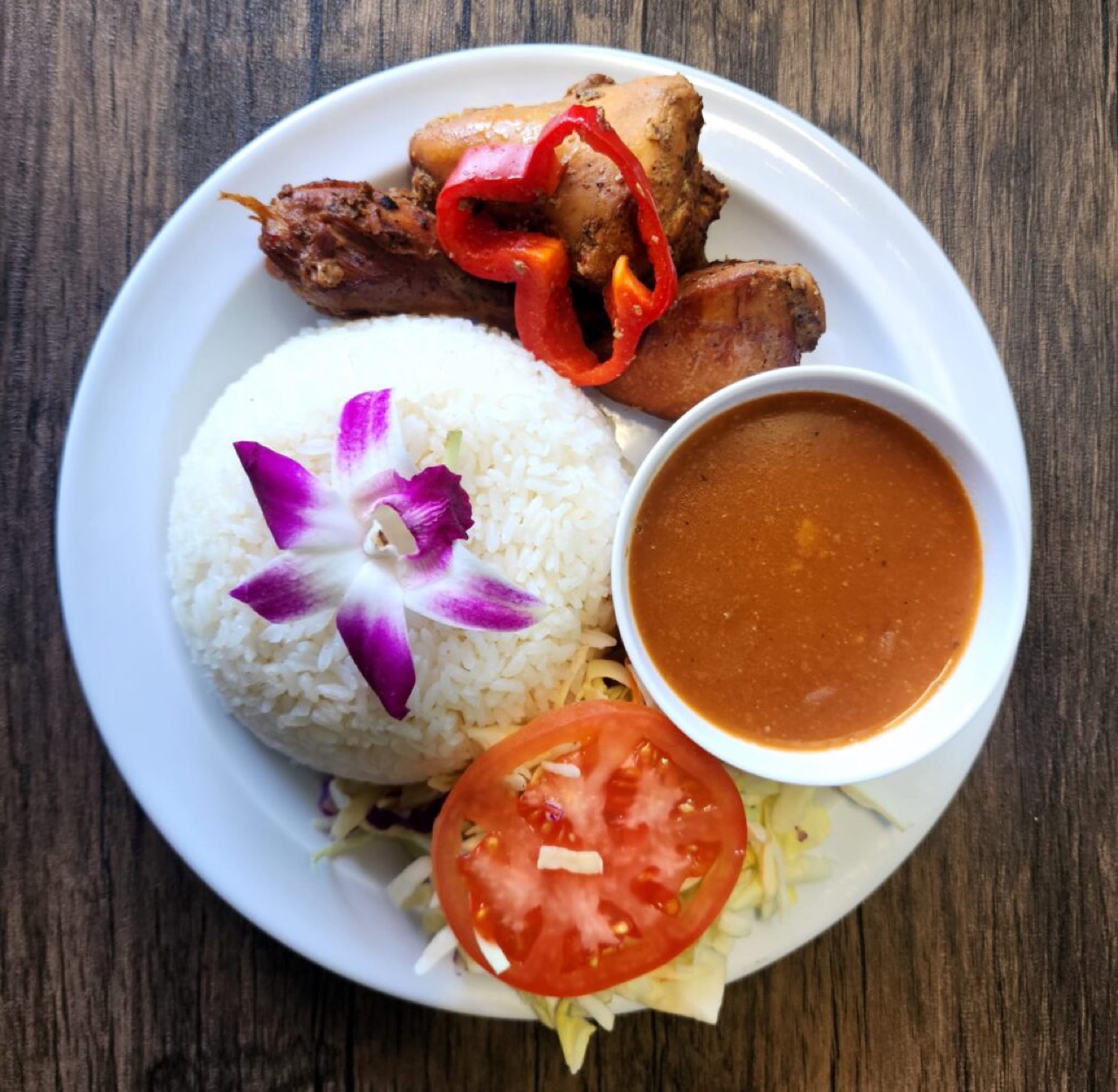 Dominican plato — yellow rice, roast chicken and fried plantain with an orchid garnish
